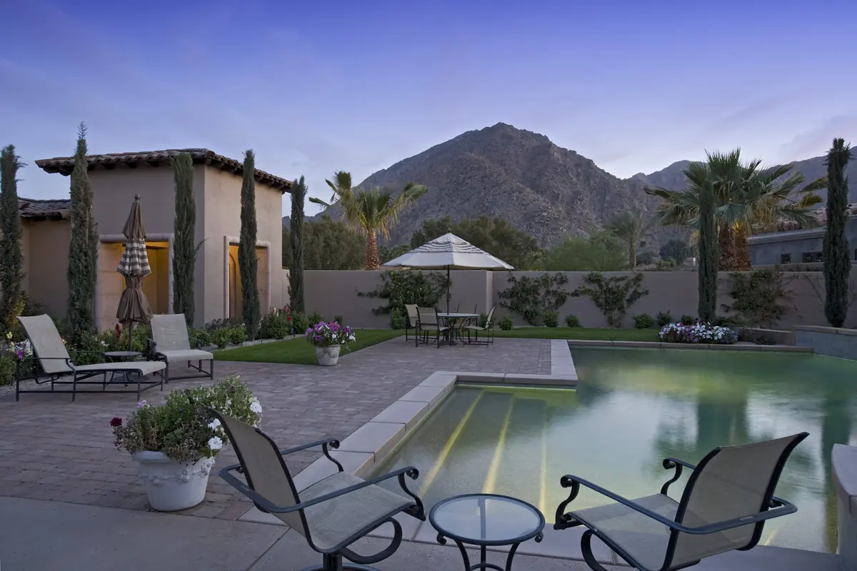 Luxury backyard with a pool, stone patio and mountain views at dusk
