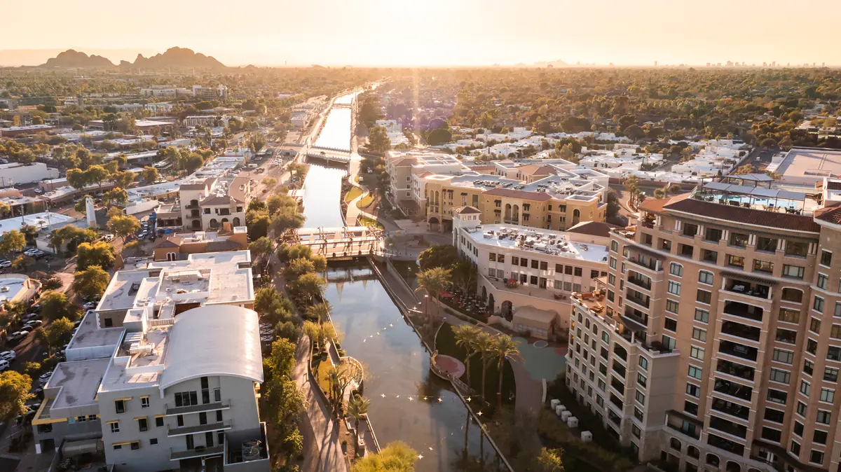 Golden-hour aerial of a canal and walking path winding through a Scottsdale residential and shopping district