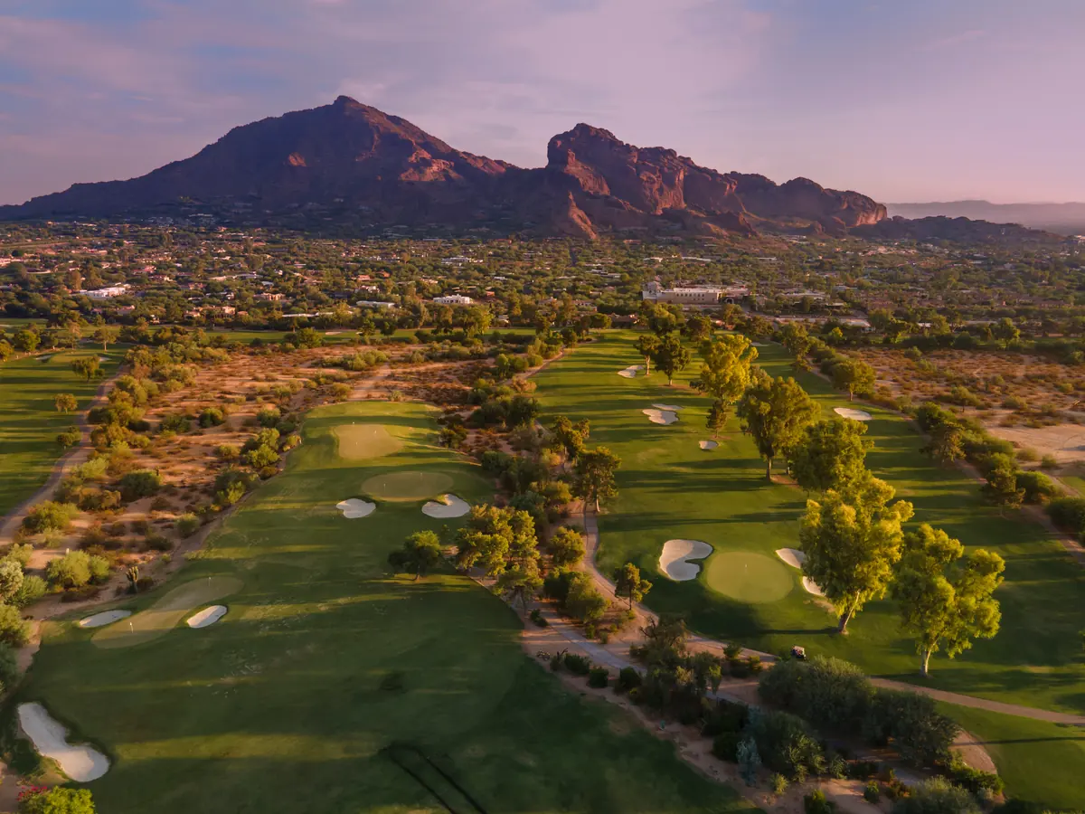 Manicured golf course at dusk with desert mountains in the background, typical of Scottsdale green space