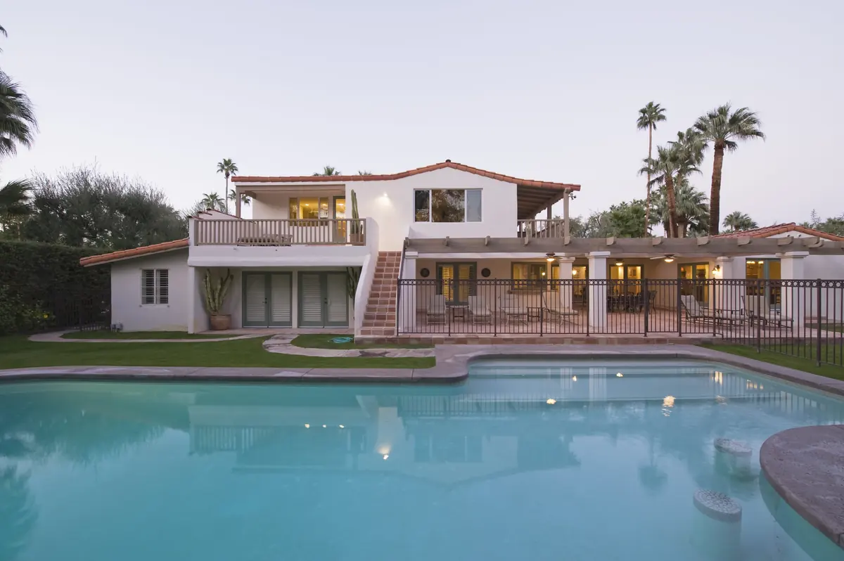 White luxury home beside a swimming pool at dusk