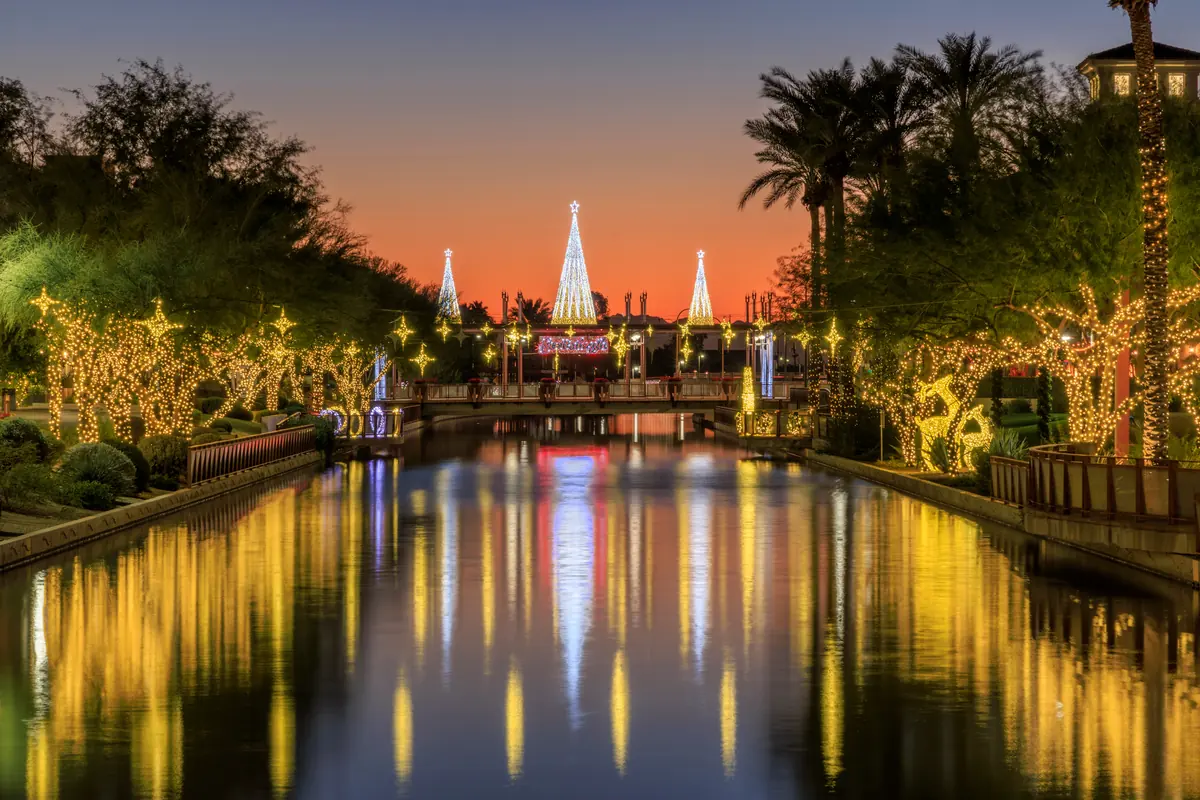 Illuminated bridge and palm trees reflected in calm water at dusk in Scottsdale